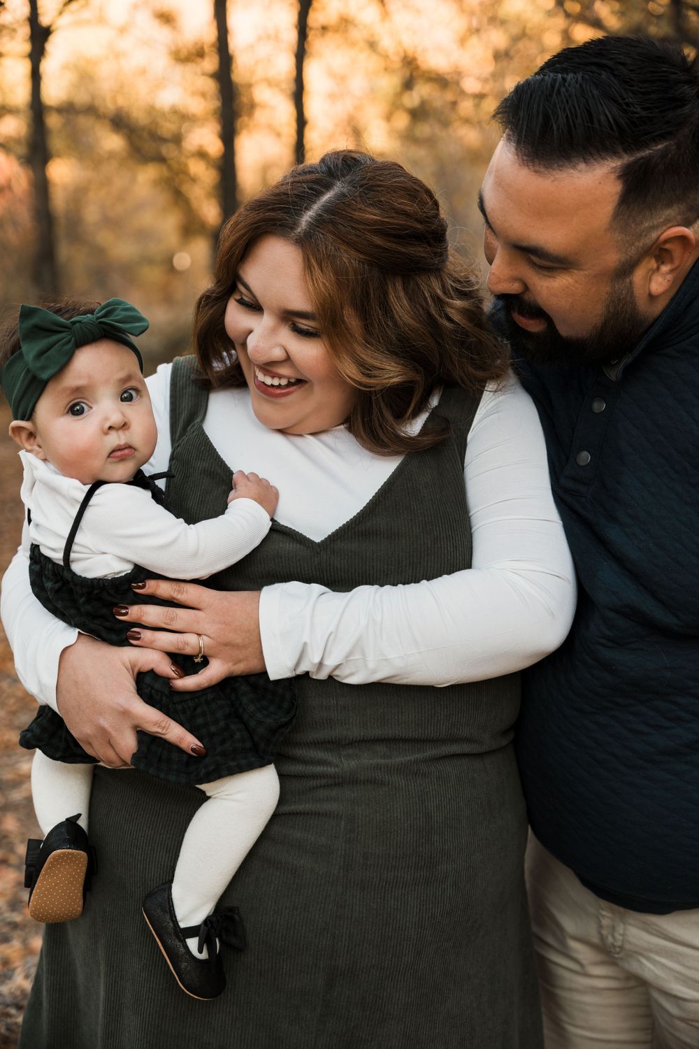 Candid family moments captured during a fall photoshoot in a wooded setting.