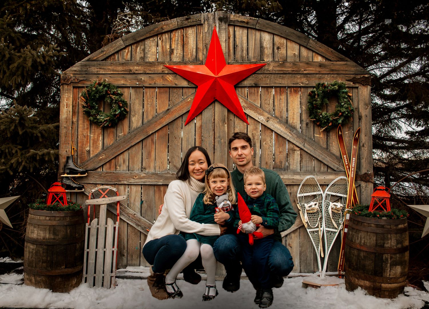 A rustic barn door backdrop with wreaths and a large red star creates a perfect holiday photo setting.