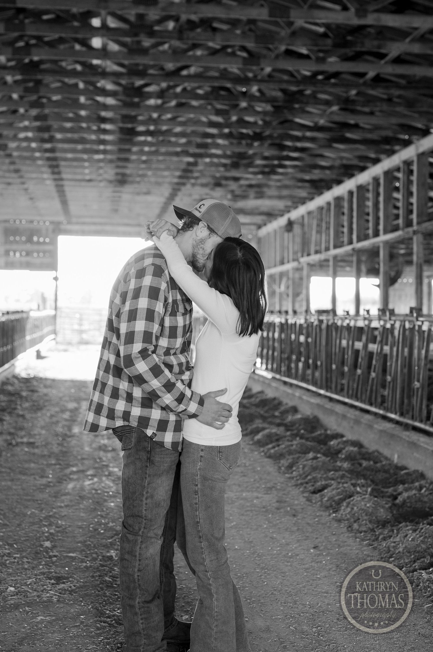 A romantic black and white moment between a couple in a rustic barn setting.