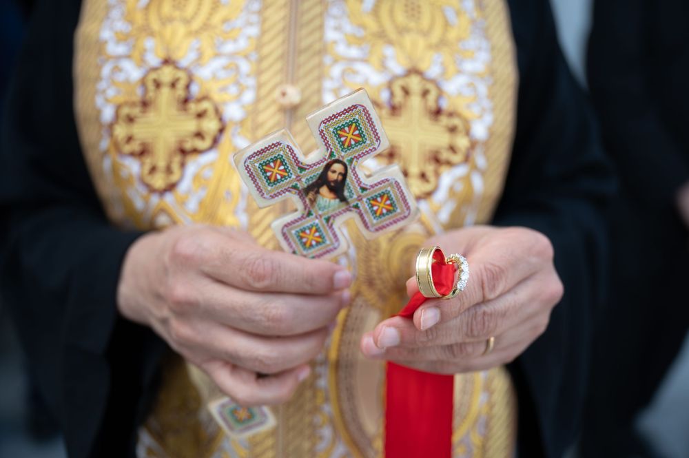 Priest holds decorative cross with Jesus icon during Coptic Orthodox wedding ceremony.