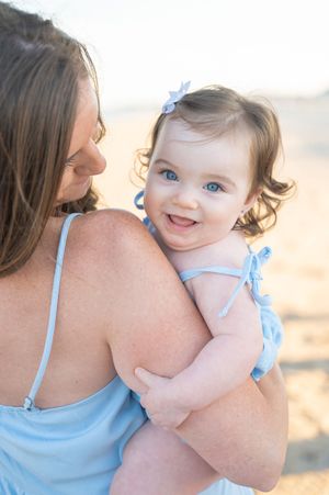 A littler girl smiling over Moms shoulder.