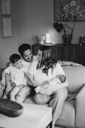 Family sitting on sofa, smiling at each other.