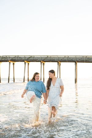 Two girls walking in water while holding hands.