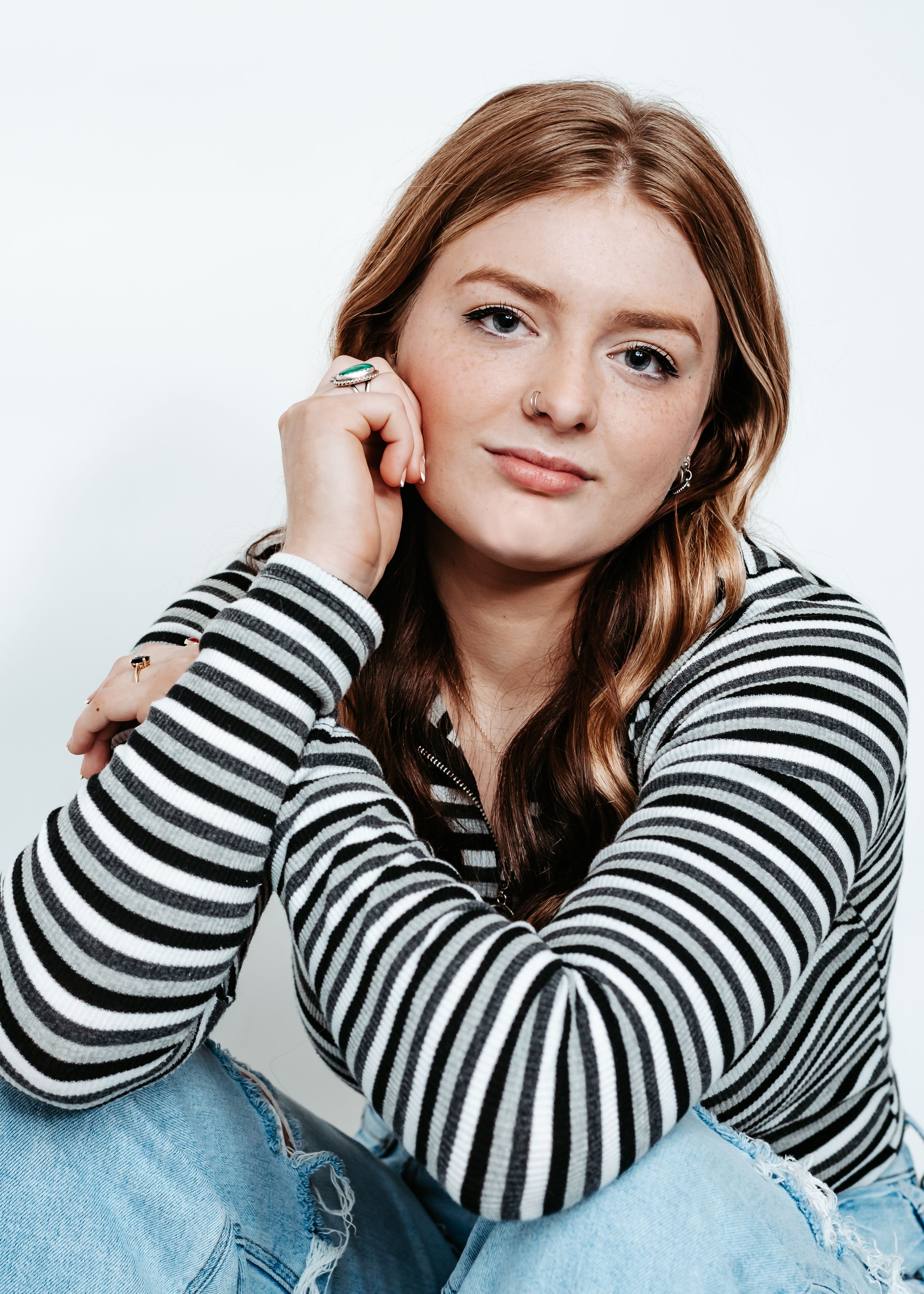 Portrait of woman in striped sweater and jeans against white background.