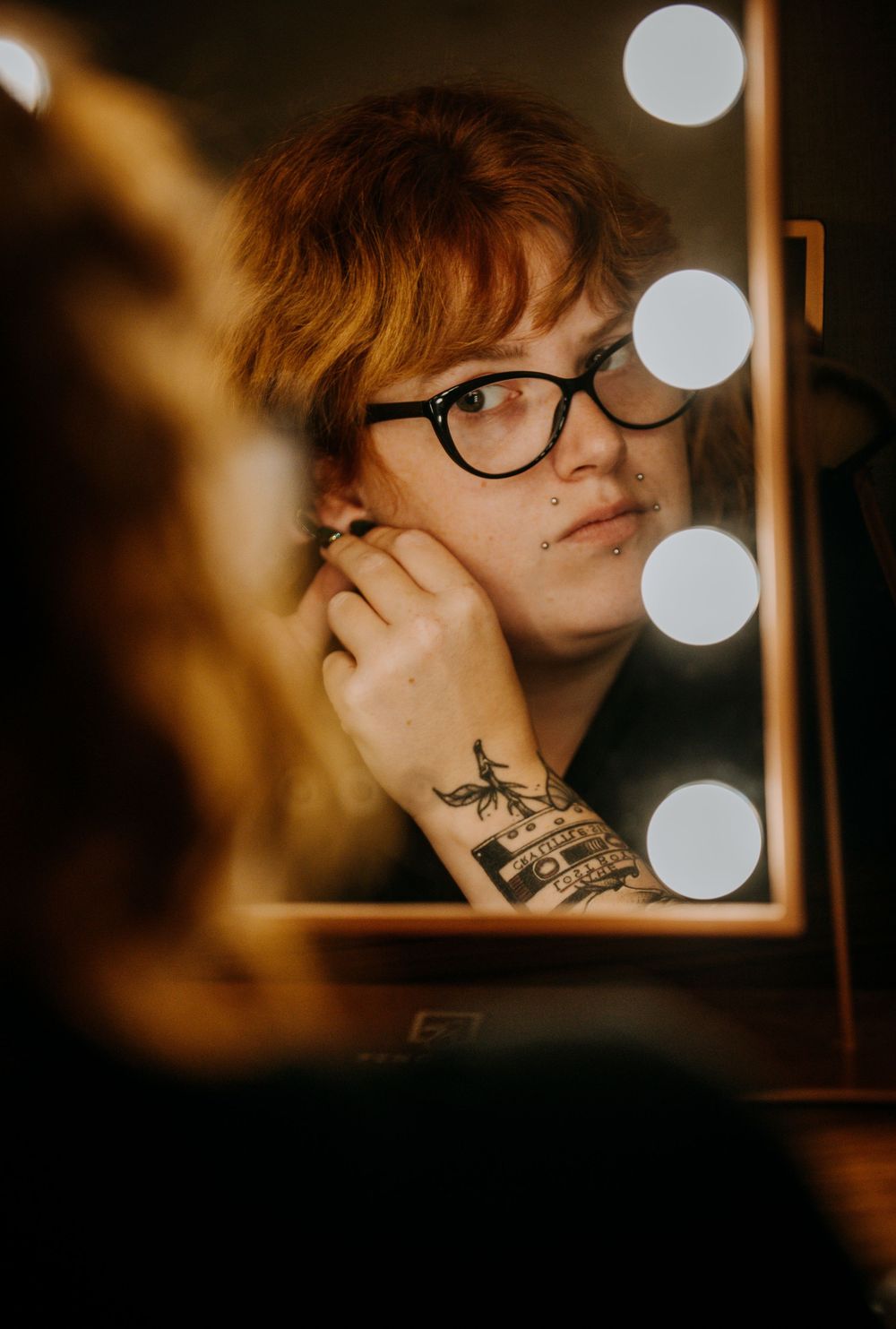 Moody side profile portraits in warm lighting show a figure with glasses and neck tattoo in a cinematic style.