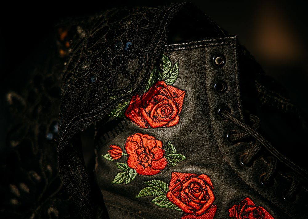 Decorative red rose embroidery pattern on black fabric with delicate floral stitching details.