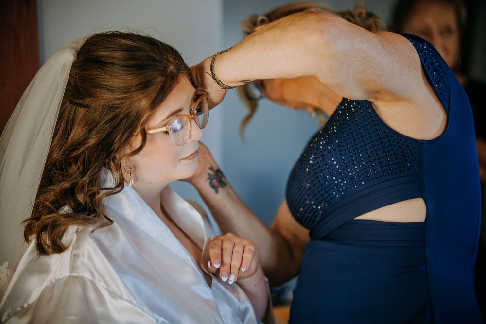 Wedding party getting ready with hair and makeup preparations in a bright room.