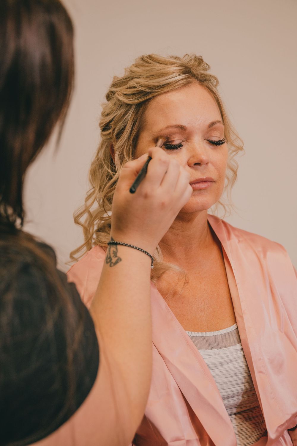 Professional makeup artist applies eyeshadow during bridal preparation.
