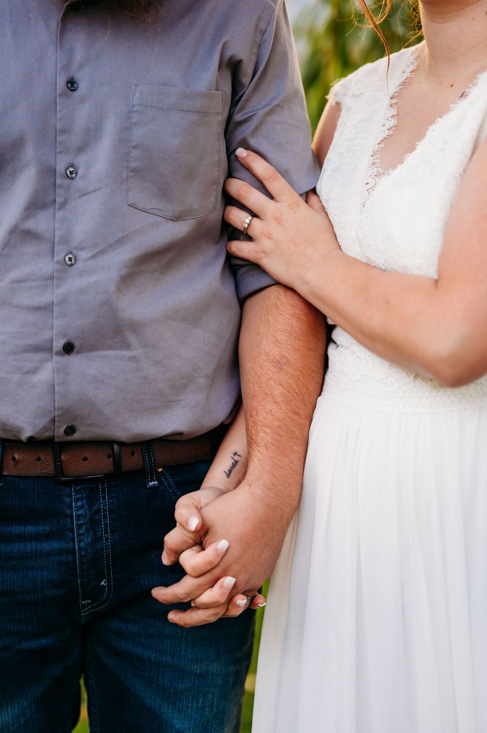 Detail shot of couple's hands and formal attire showing tender connection and wedding day fashion.
