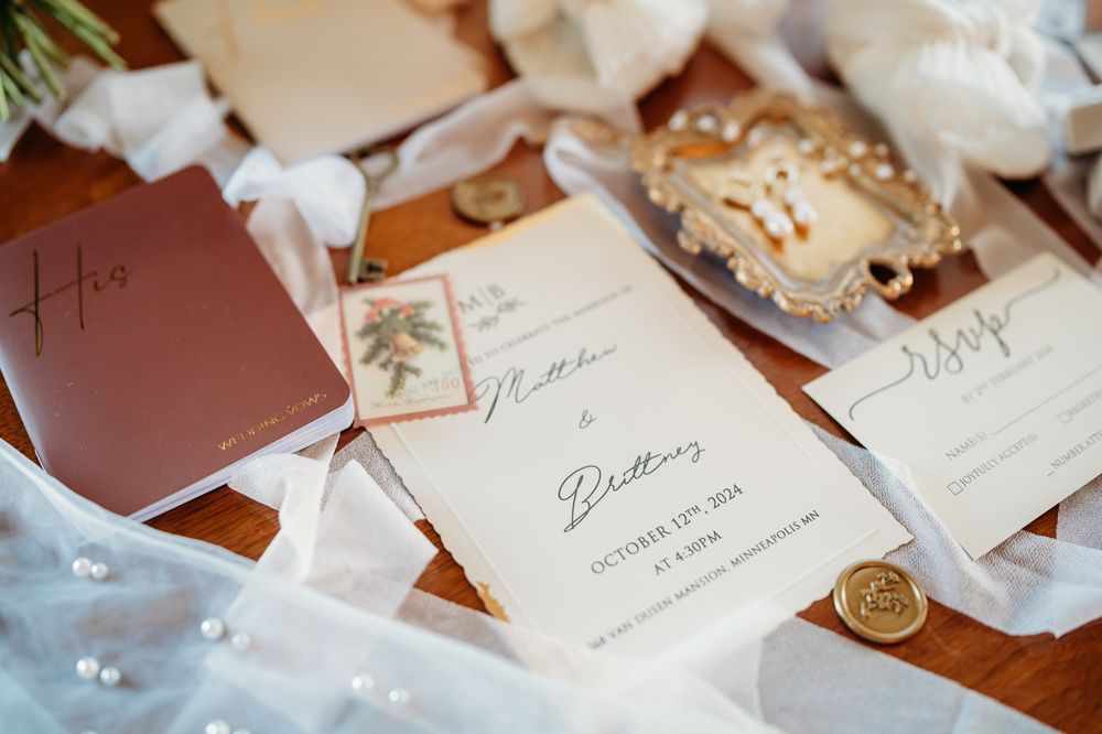 Elegant wedding invitation suite with white paper and wax seals displayed on wooden surface with soft fabric details.