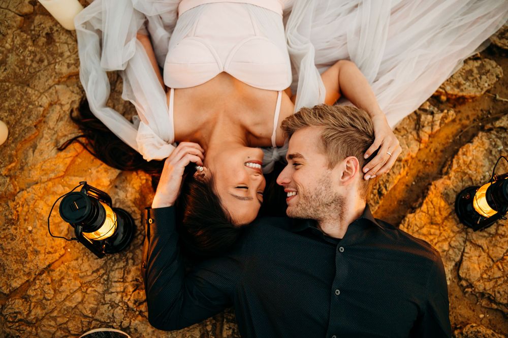 A couple lies on autumn ground sharing an intimate moment during their photoshoot.