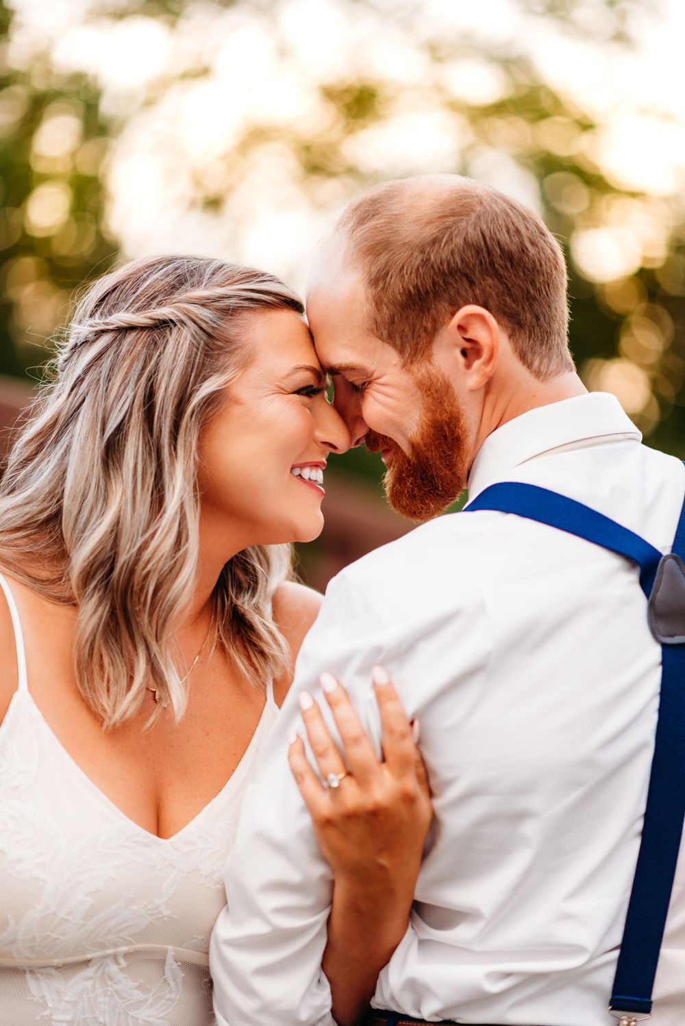 An intimate moment between newlyweds sharing laughter in natural sunset lighting.