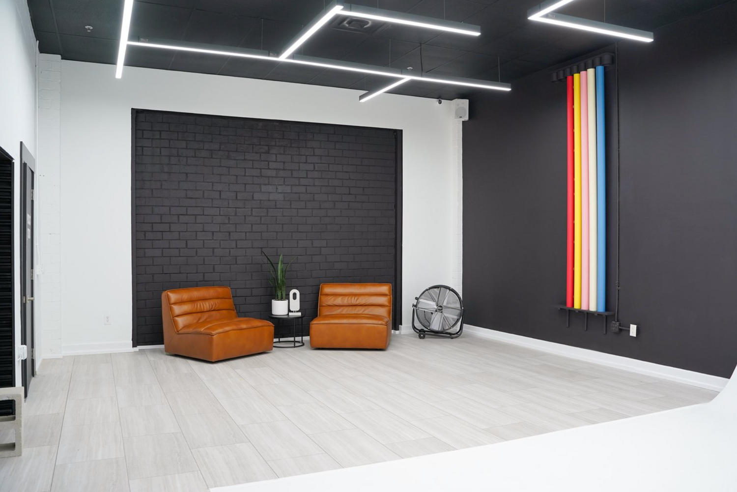 Modern photography studio interior with orange chairs and geometric lighting fixtures.