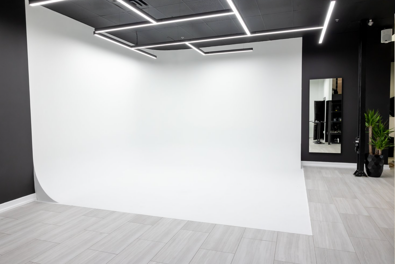 Clean white photography backdrop in a modern studio with geometric ceiling lights.
