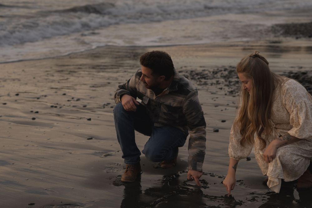 Two people explore tide pools on a cloudy beach at dusk on Ruby Beach, Olympic National Park