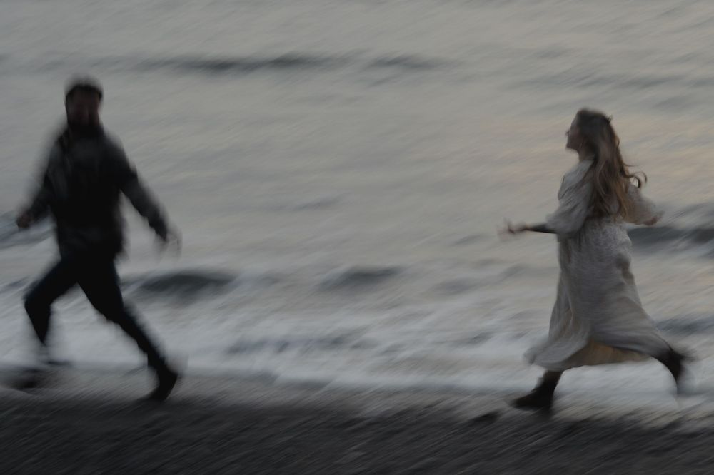 Motion blurred image of couple running along beach at twilight on Ruby Beach, Olympic National Park.
