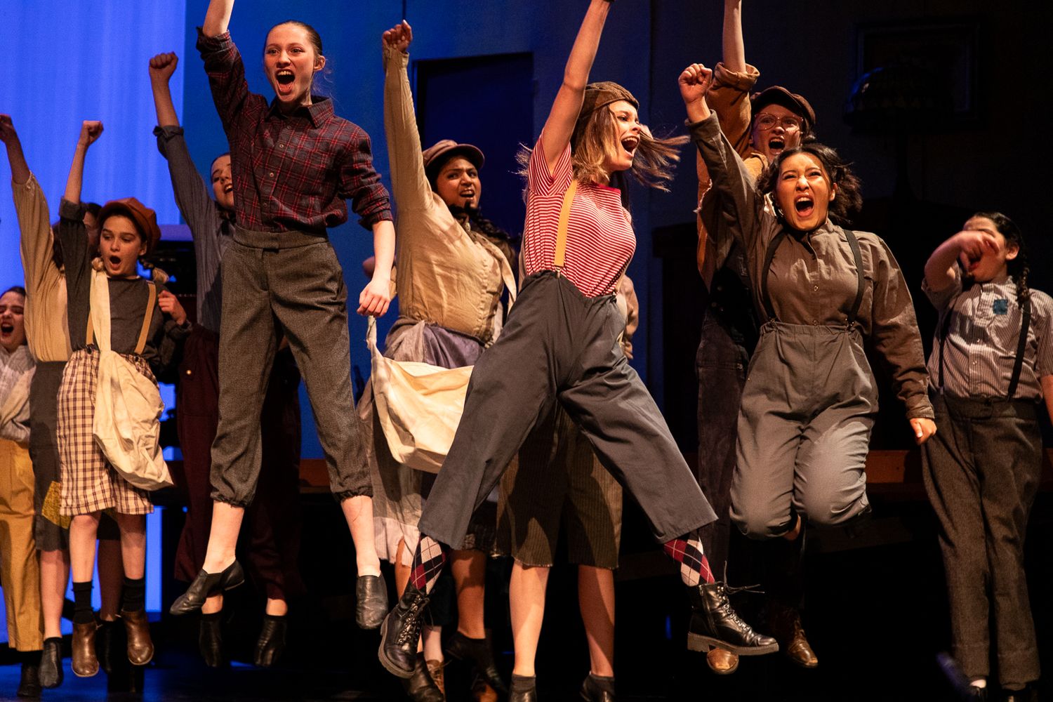 Live theater photography; students cheering and jumping during a performance of Newsies; Clarissa Anello