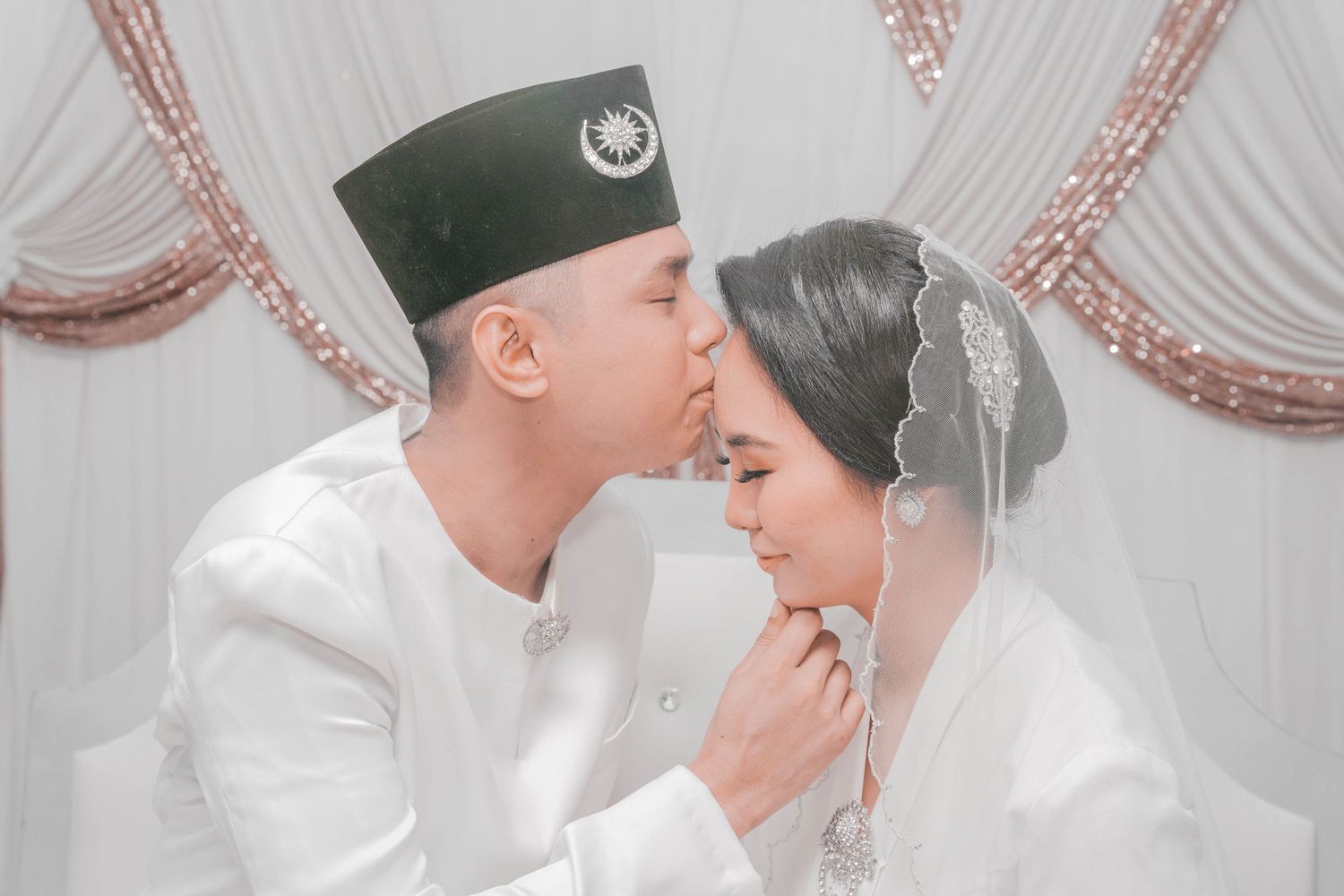 An intimate wedding portrait against rose gold and white draped backdrop.