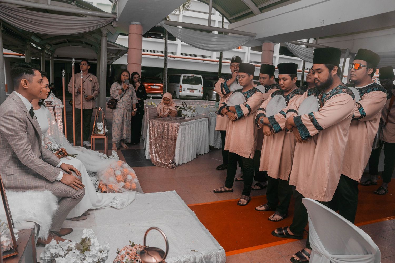 Musicians in matching peach uniforms perform for wedding guests at an indoor reception.