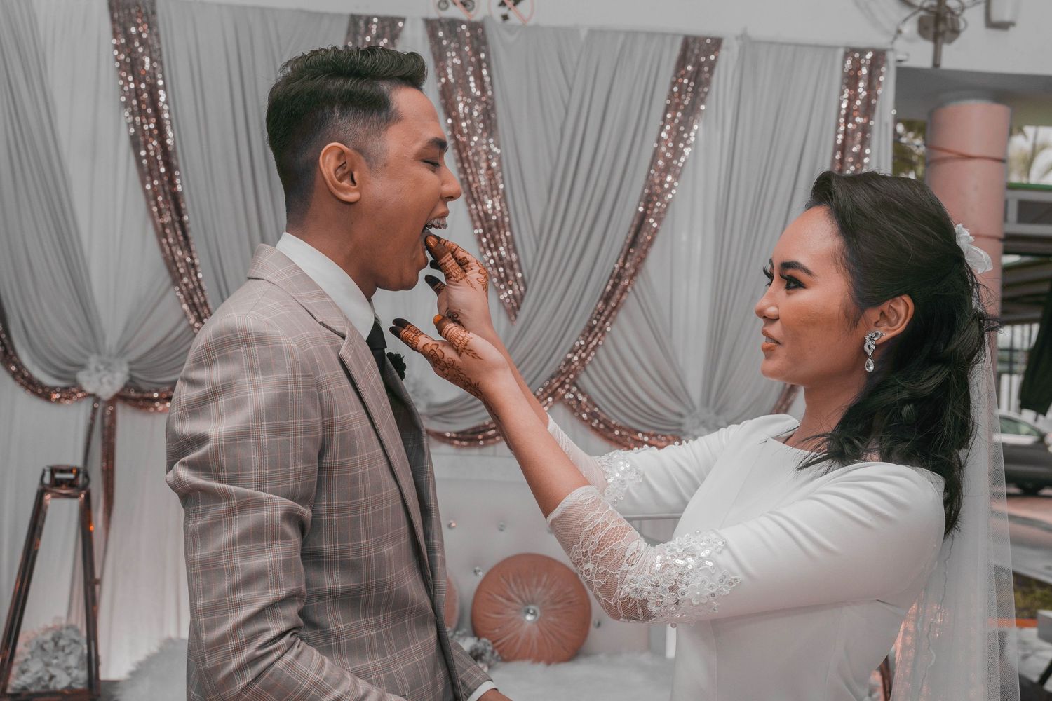 A couple shares an intimate moment during their wedding reception against draped fabric backdrop.