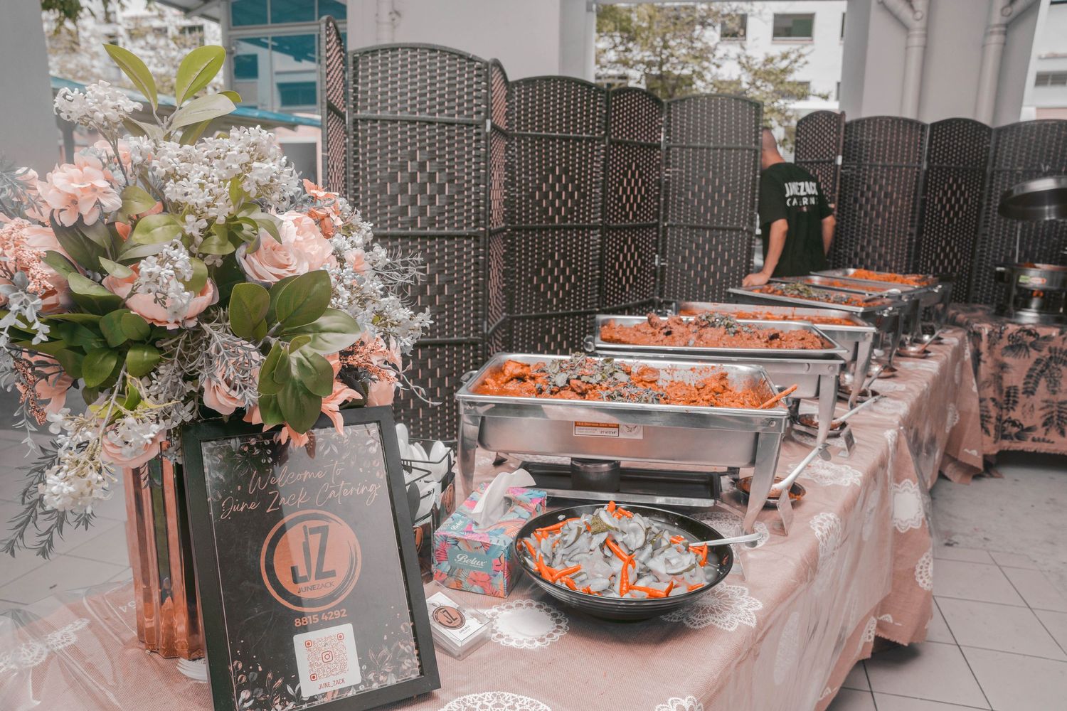 Elegant catering setup with floral arrangements and chafing dishes.