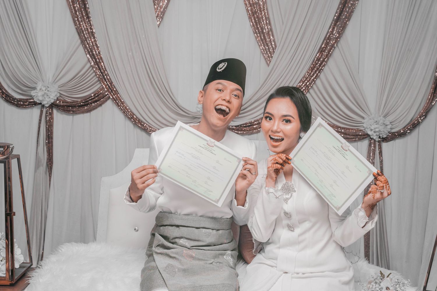 A couple displaying their marriage certificates with joy at their wedding ceremony.
