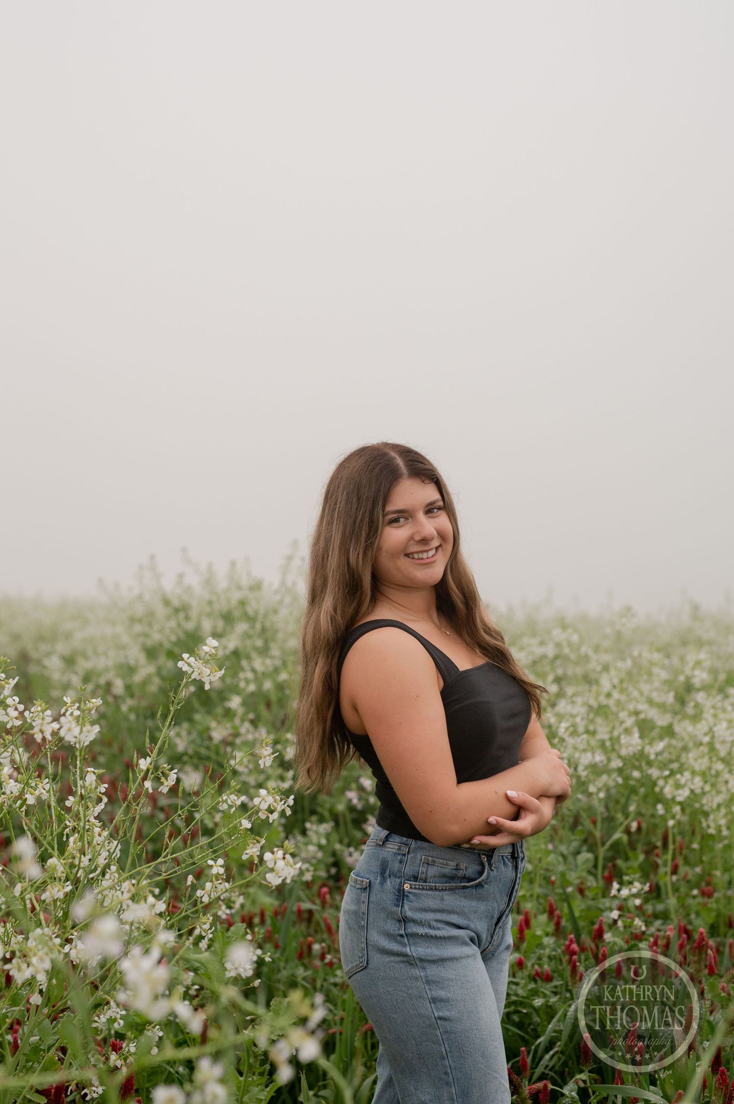 Side view portrait in a summer meadow wearing casual attire surrounded by delicate white wildflowers.