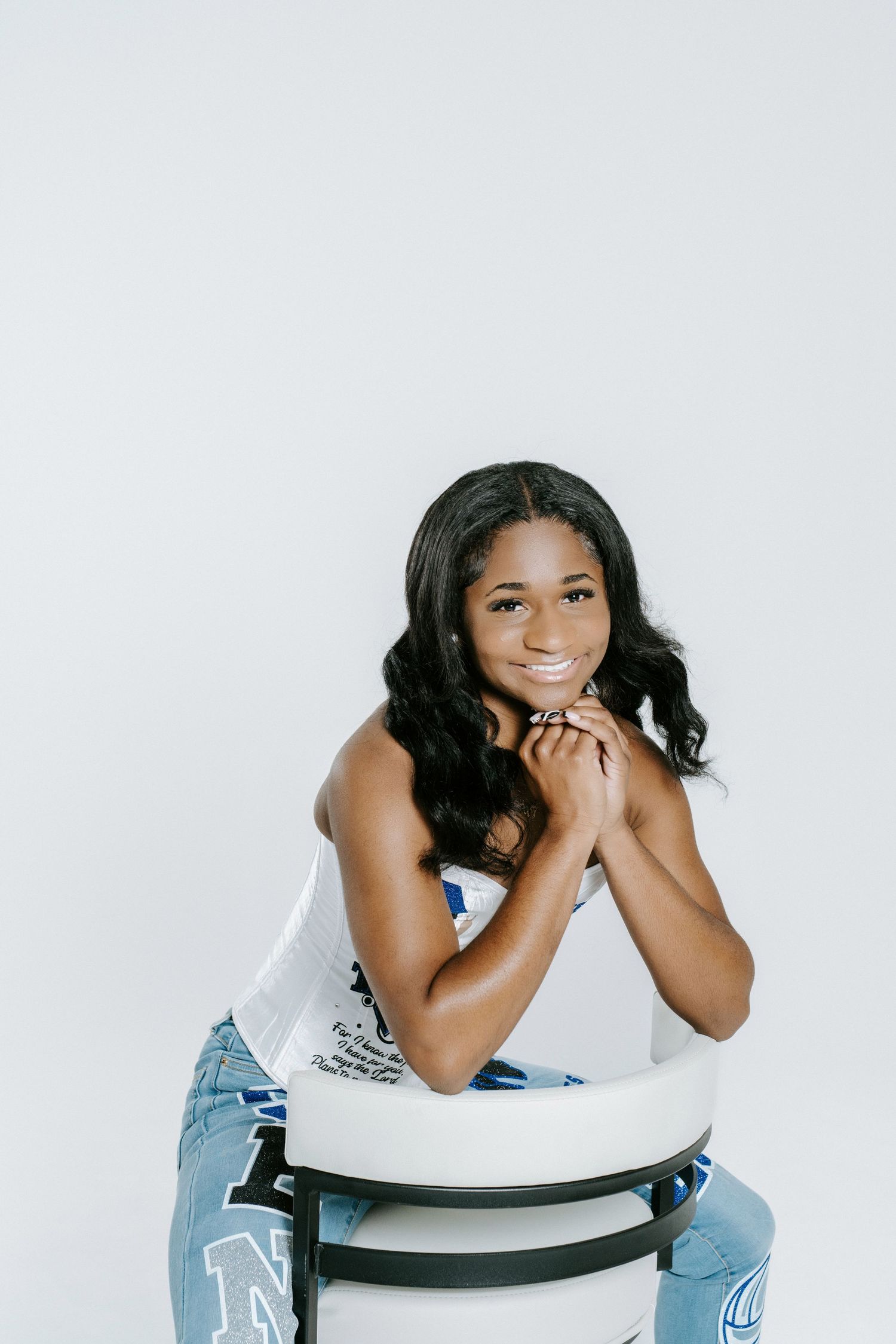 A stylish photo shoot against a white backdrop featuring poses in denim jeans and a white top.