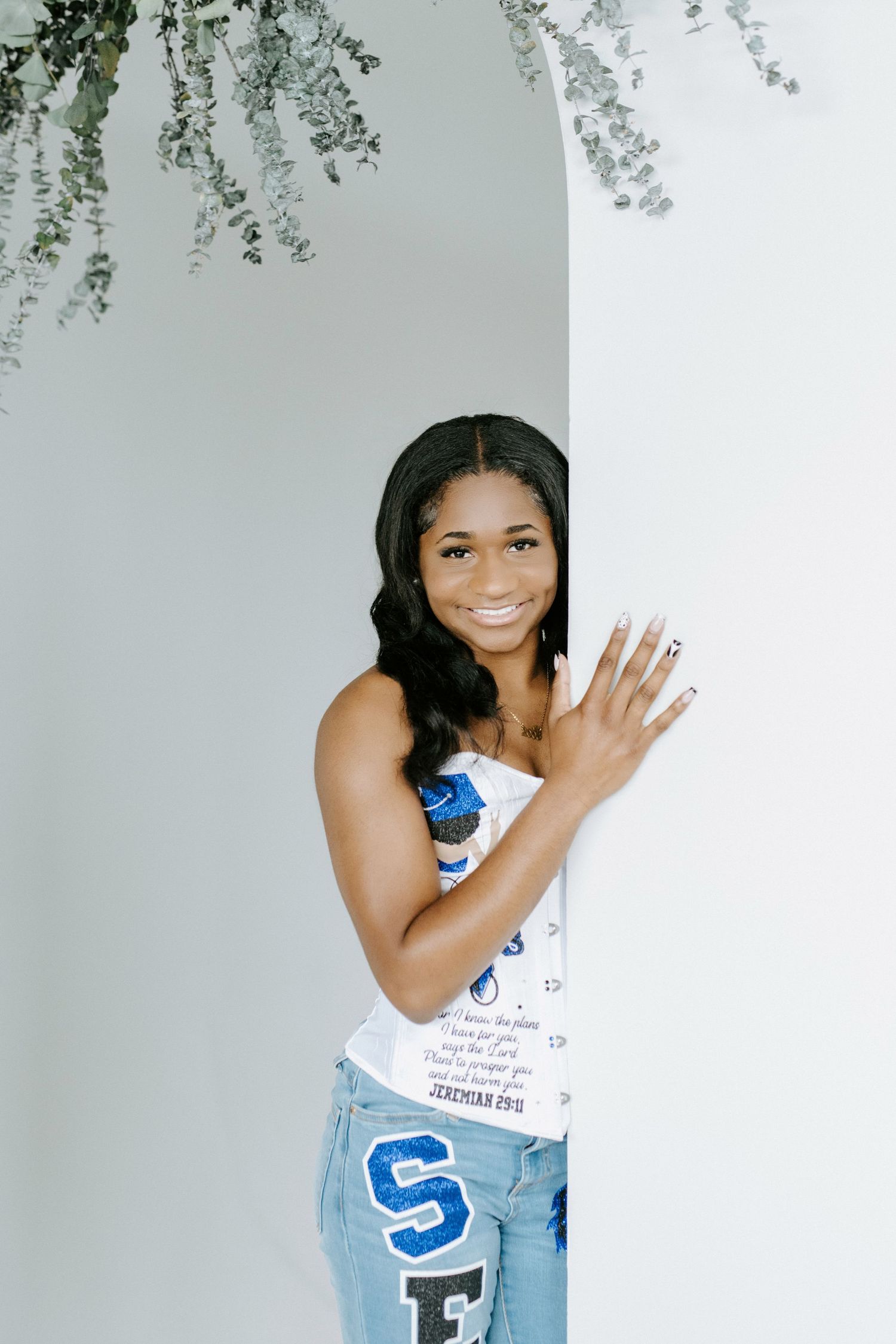Playful poses under hanging greenery in a modern minimalist studio setting.