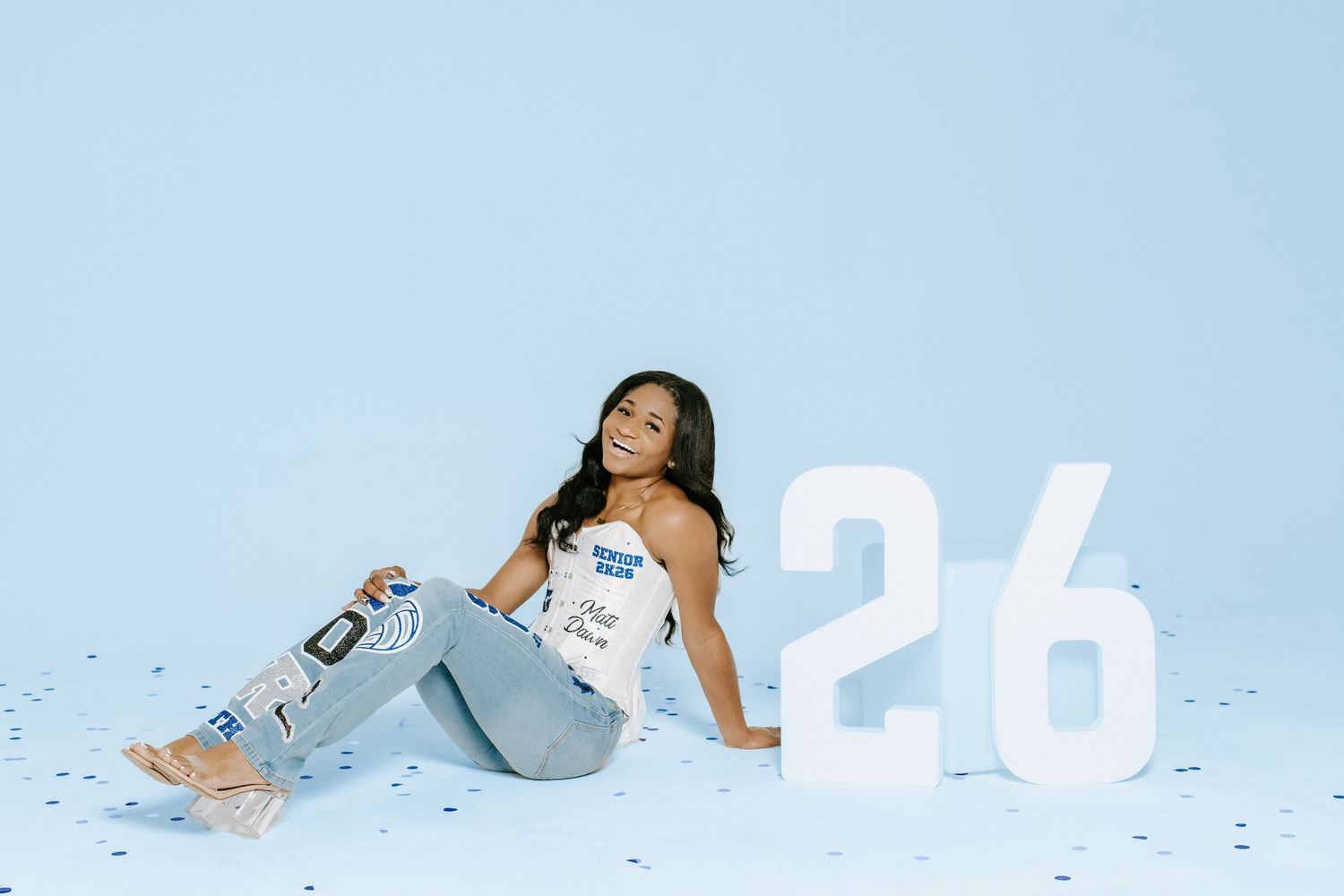 Someone lounges on a snowy winter background in a light blue outfit styled with pale accents.