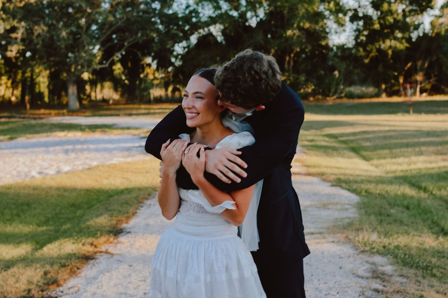 A joyful wedding moment captured outdoors with a playful dip pose between newlyweds in formal attire.