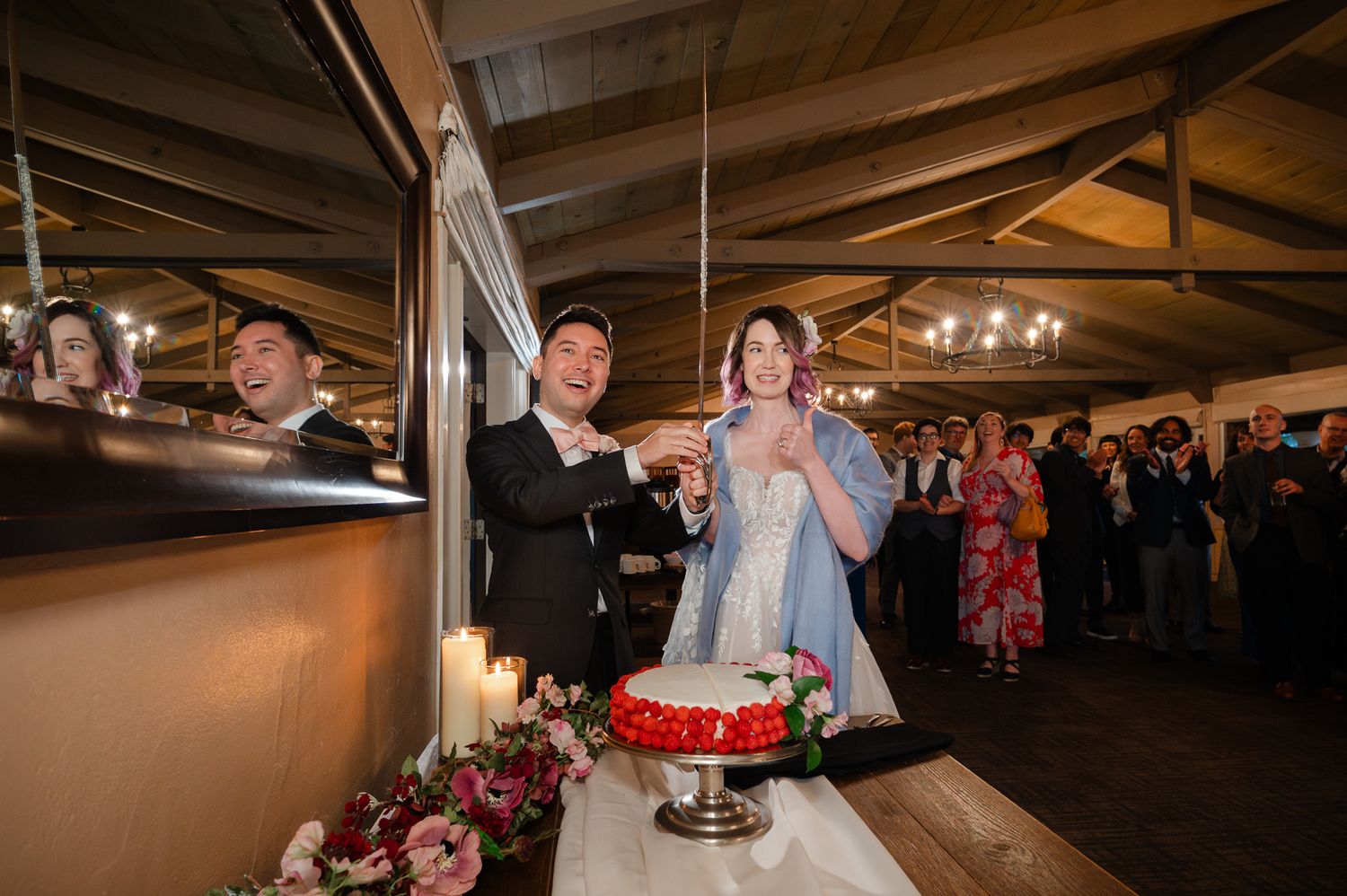Wedding guests celebrate and enjoy themselves on a dance floor under amber lighting at a reception venue.