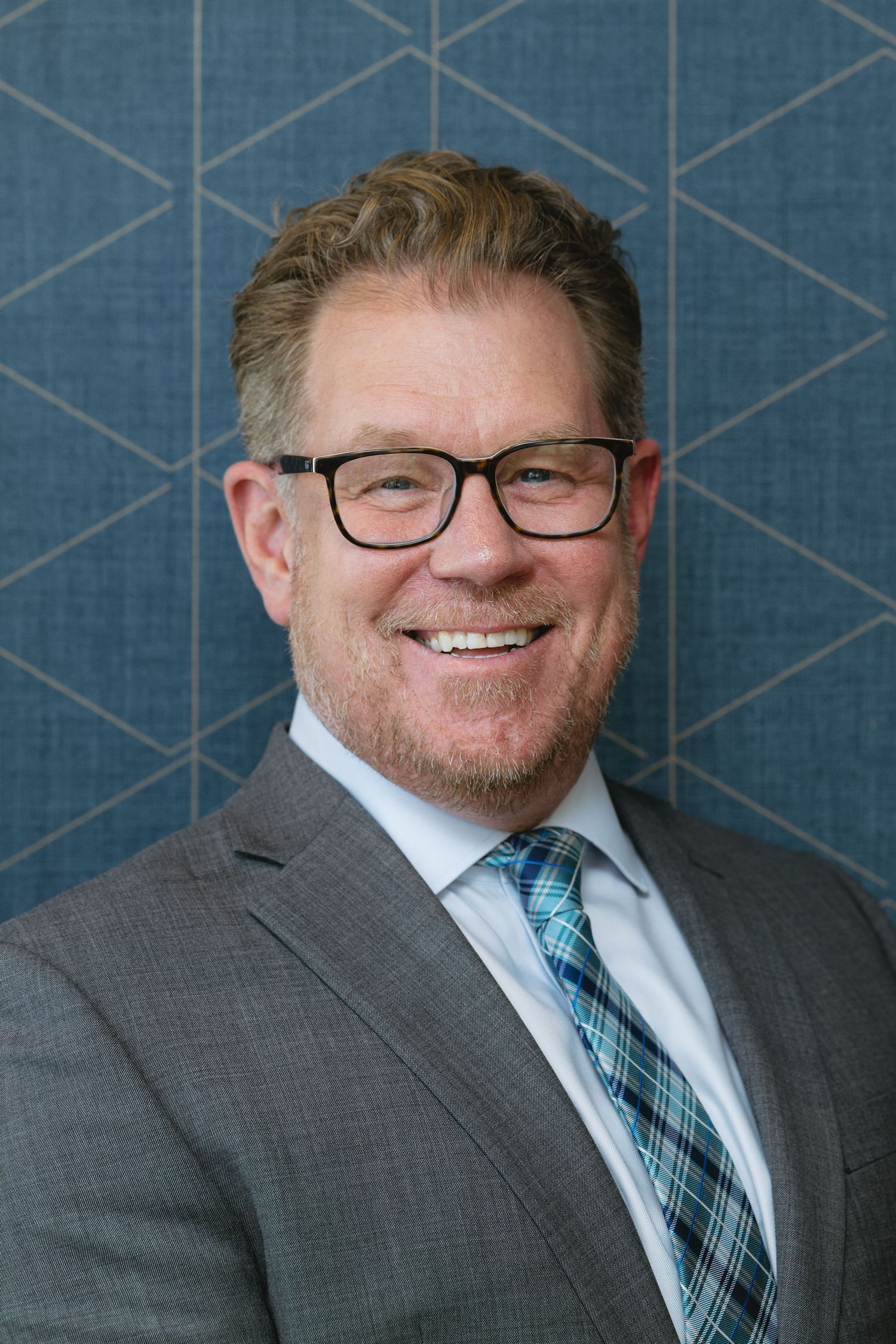 Professional headshots against blue geometric patterned background.