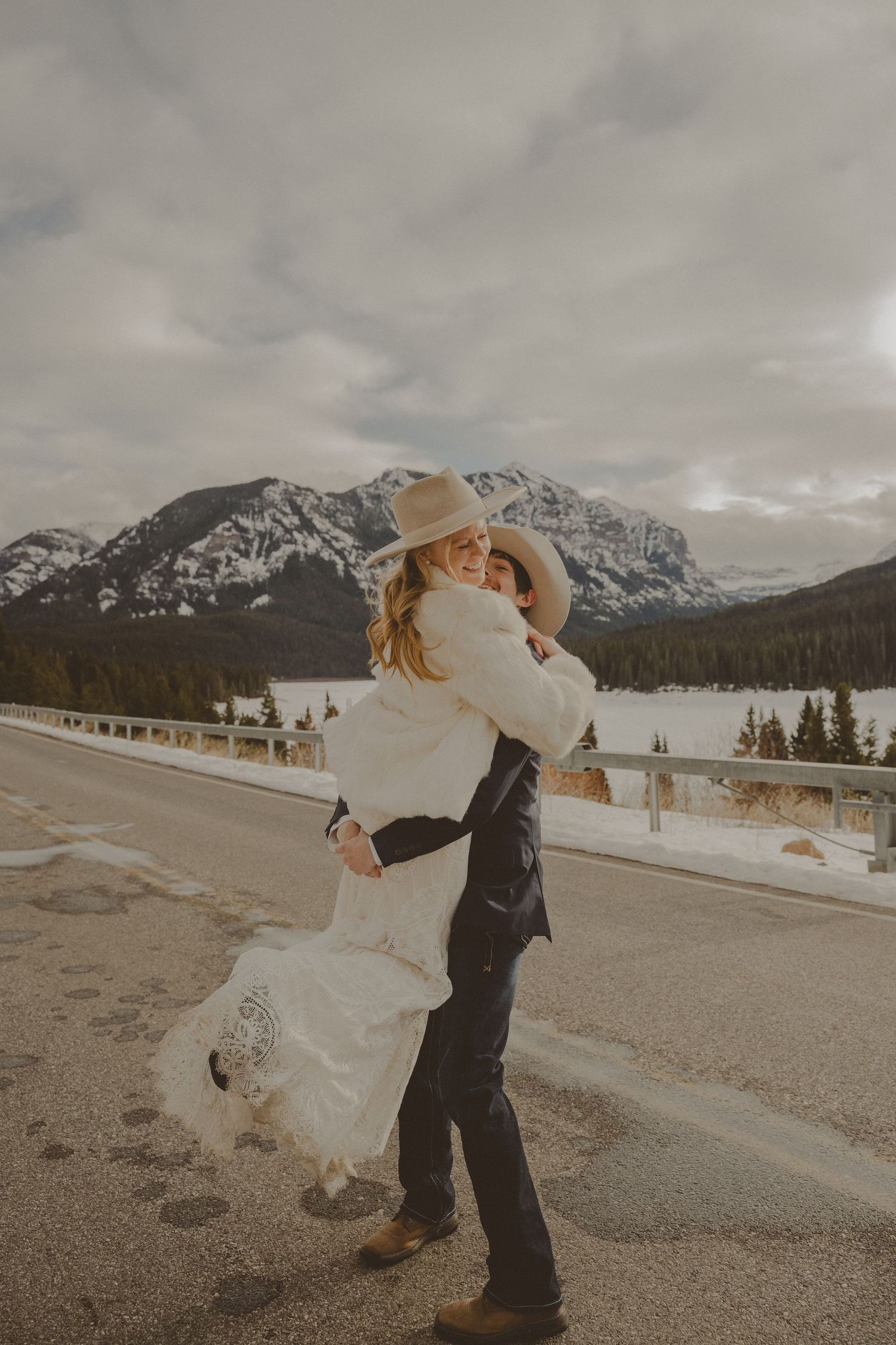 Rural wedding photoshoot with horses grazing in background meadow.