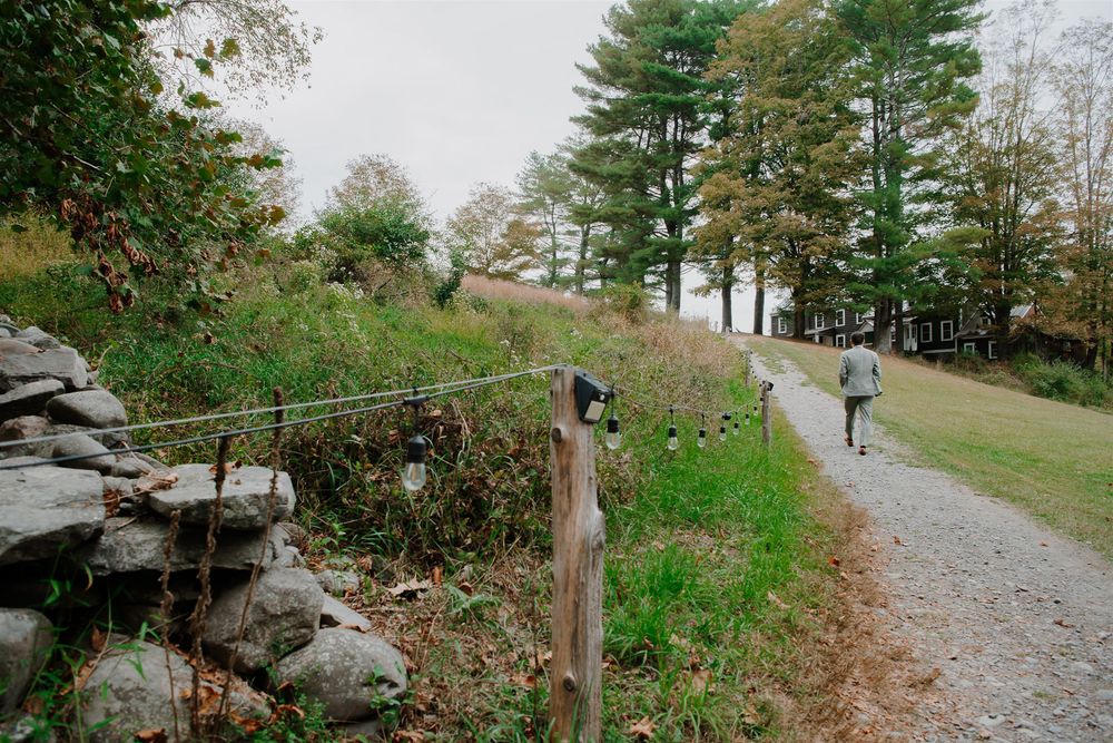 Winding gravel path leads through autumn trees and boulders in a scenic mountain landscape.