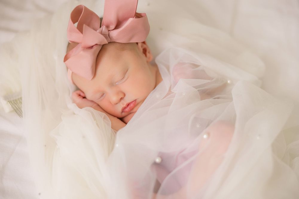 Delicate portrait of newborn draped in pink and white fabrics.