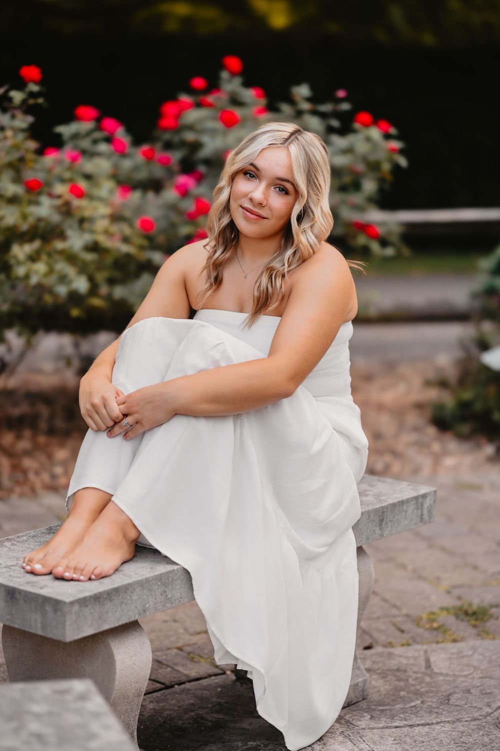 A serene scene with a white dress against red roses in a garden setting.