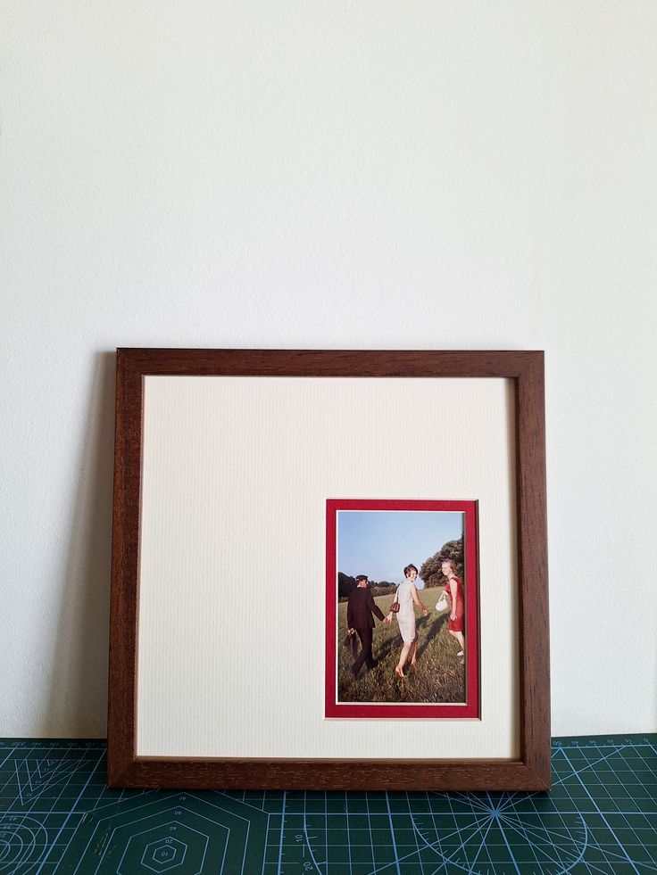 An artistic sequence showing a framed photograph gradually shrinking in size within a wooden frame against a teal background.