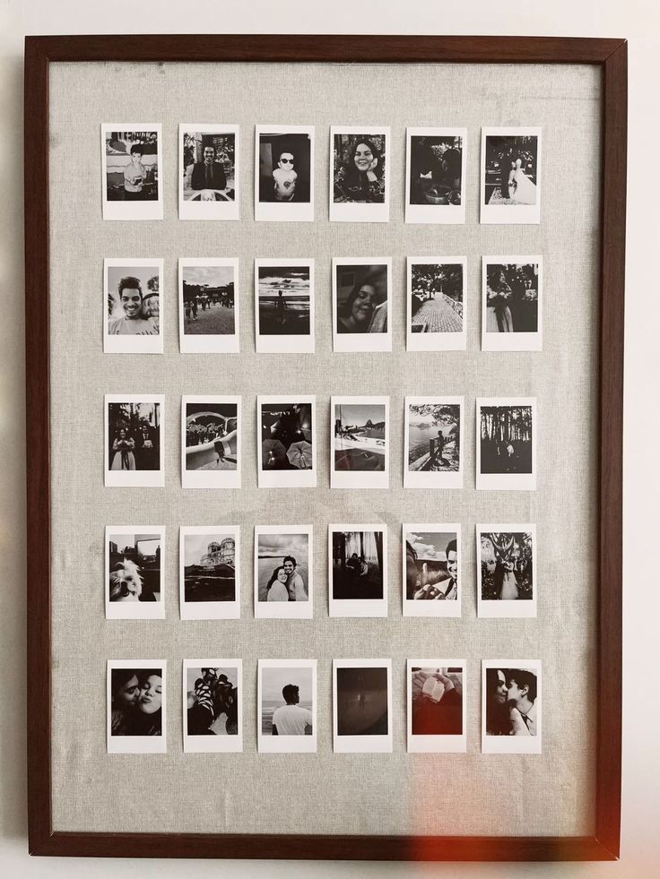A collection of vintage Polaroid photographs arranged in a grid pattern within a brown wooden frame mounted on a wall.