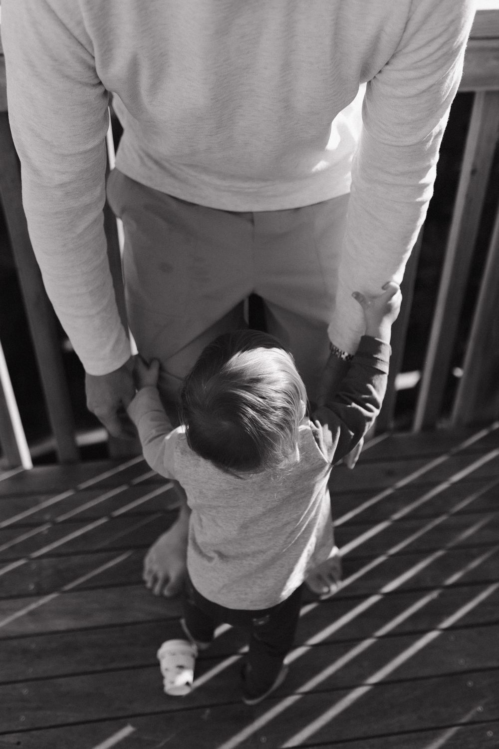 Black and white photo showing shadows and figures moving on wooden deck planks.