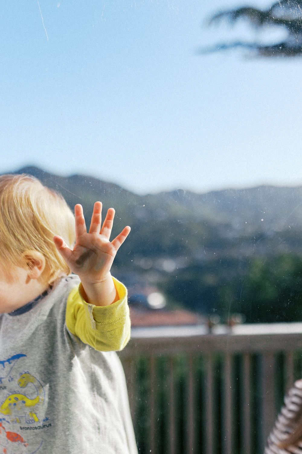 Child playing outside on deck with mountains visible in background.