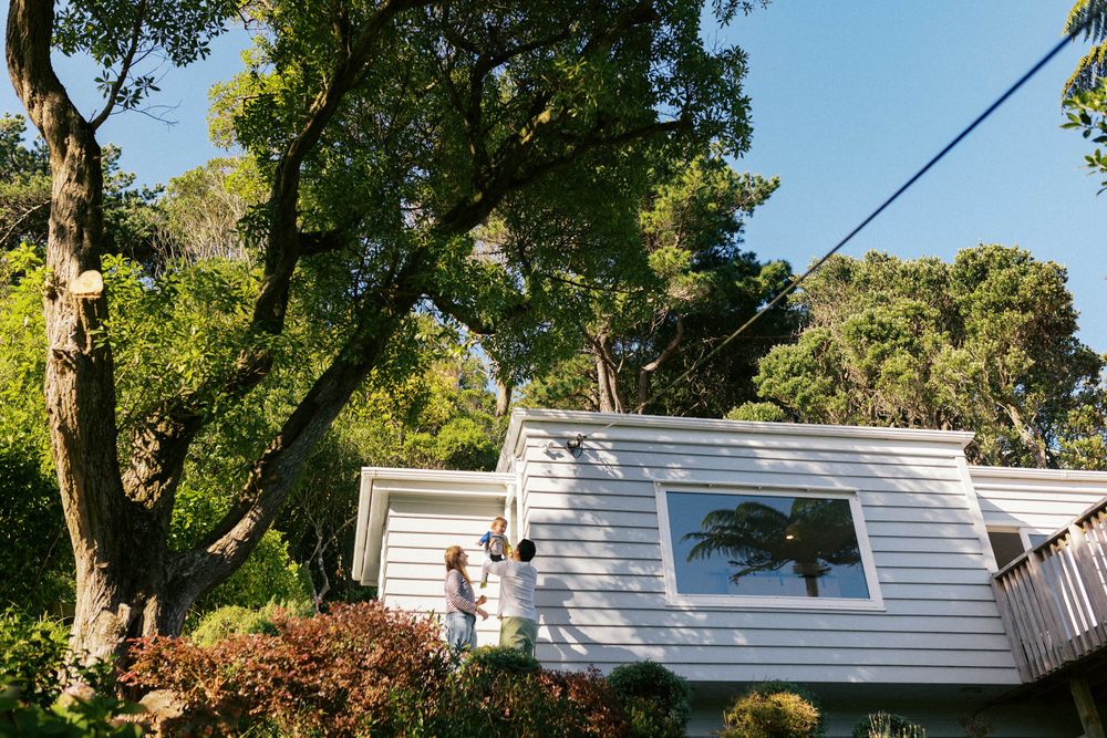 White caravan trailer parked under leafy green trees on sunny day.