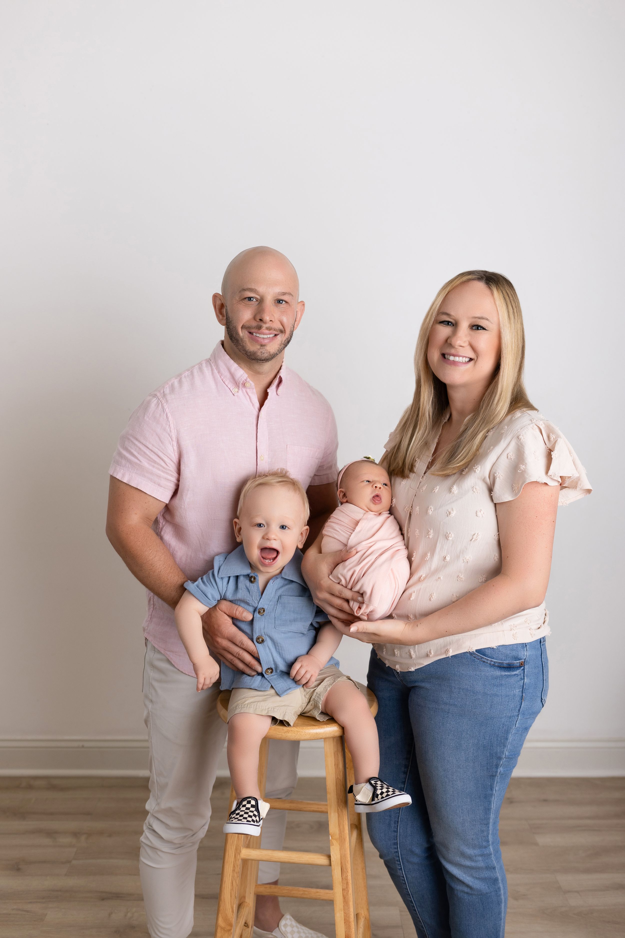 Family poses together in a series of candid shots showing playful moments with their young children against a white wall.