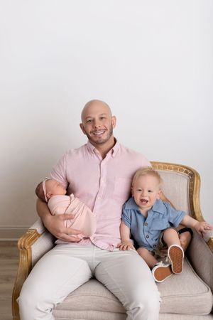 Two people sit together on a beige couch sharing joyful moments in coordinated pink and blue outfits.