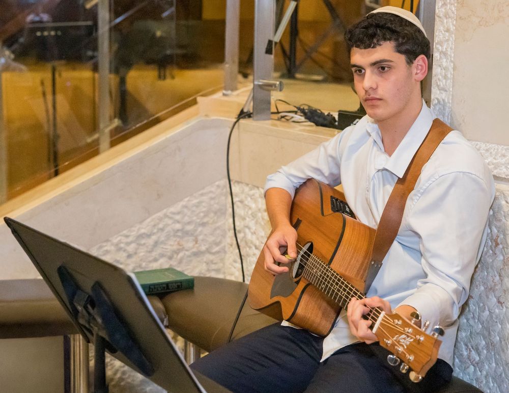 Musicians perform with acoustic guitars at an elegant indoor event venue with warm lighting.