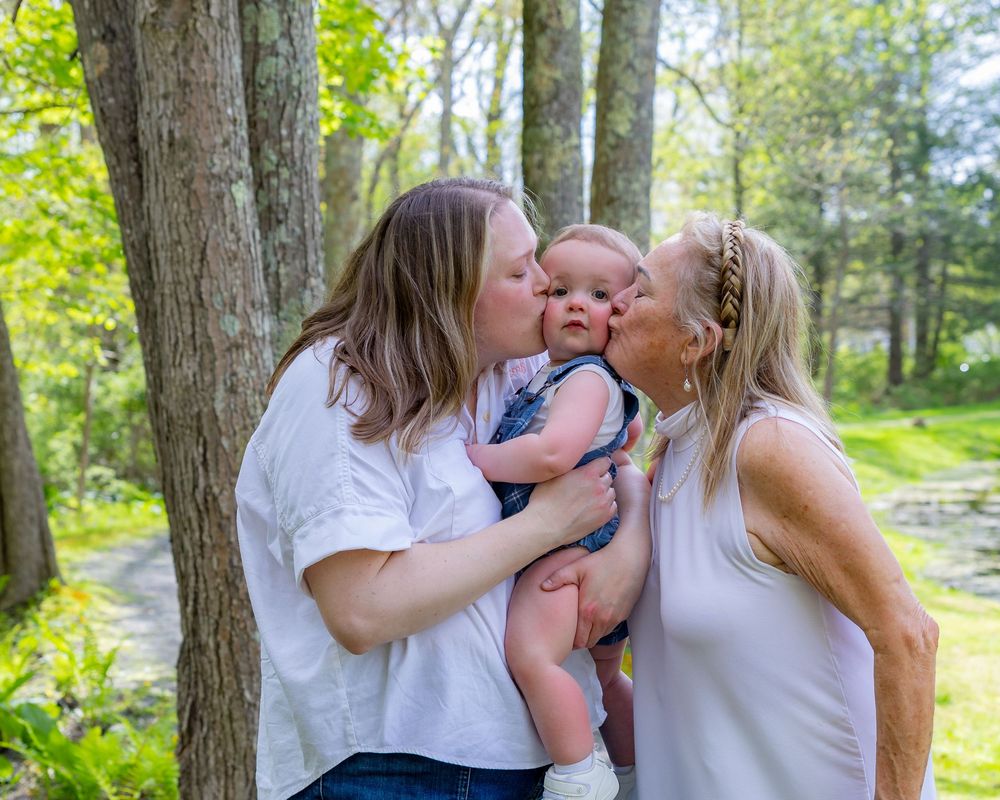 Outdoor family moments of mother, grandmother & baby captured in natural lighting among trees and greenery in Sudbury, MA.