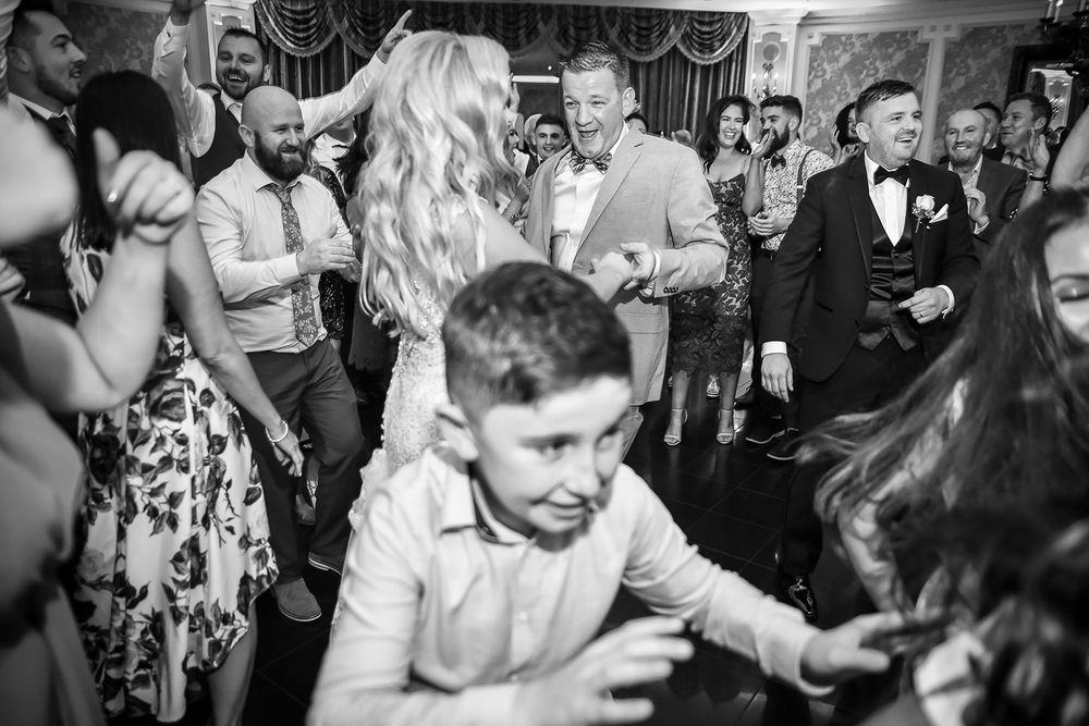 People dancing and celebrating at a lively wedding reception party in black and white photography.