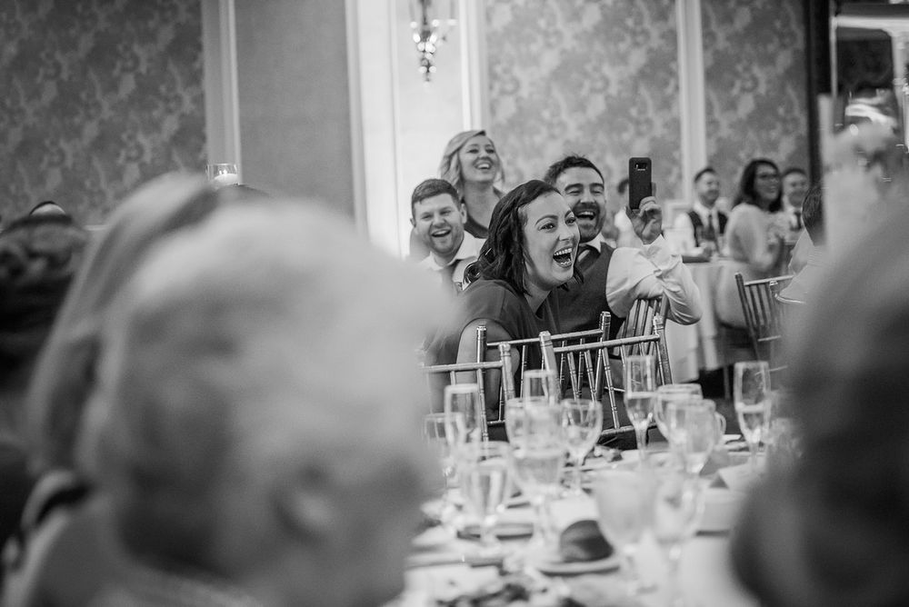 Wedding guests laugh and enjoy themselves during a celebratory reception dinner at elegant tables.