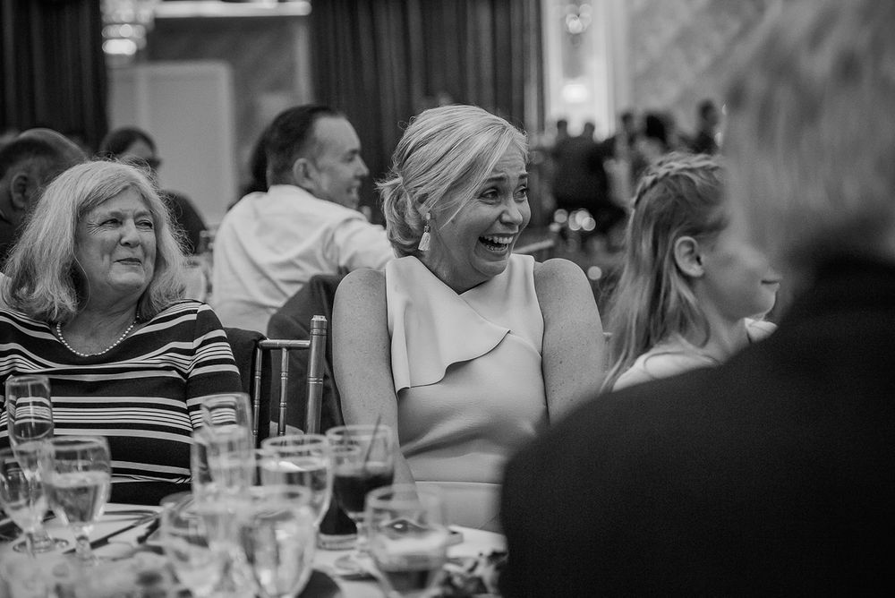 Group of people enjoying a lively conversation and laughter during dinner at a restaurant table.