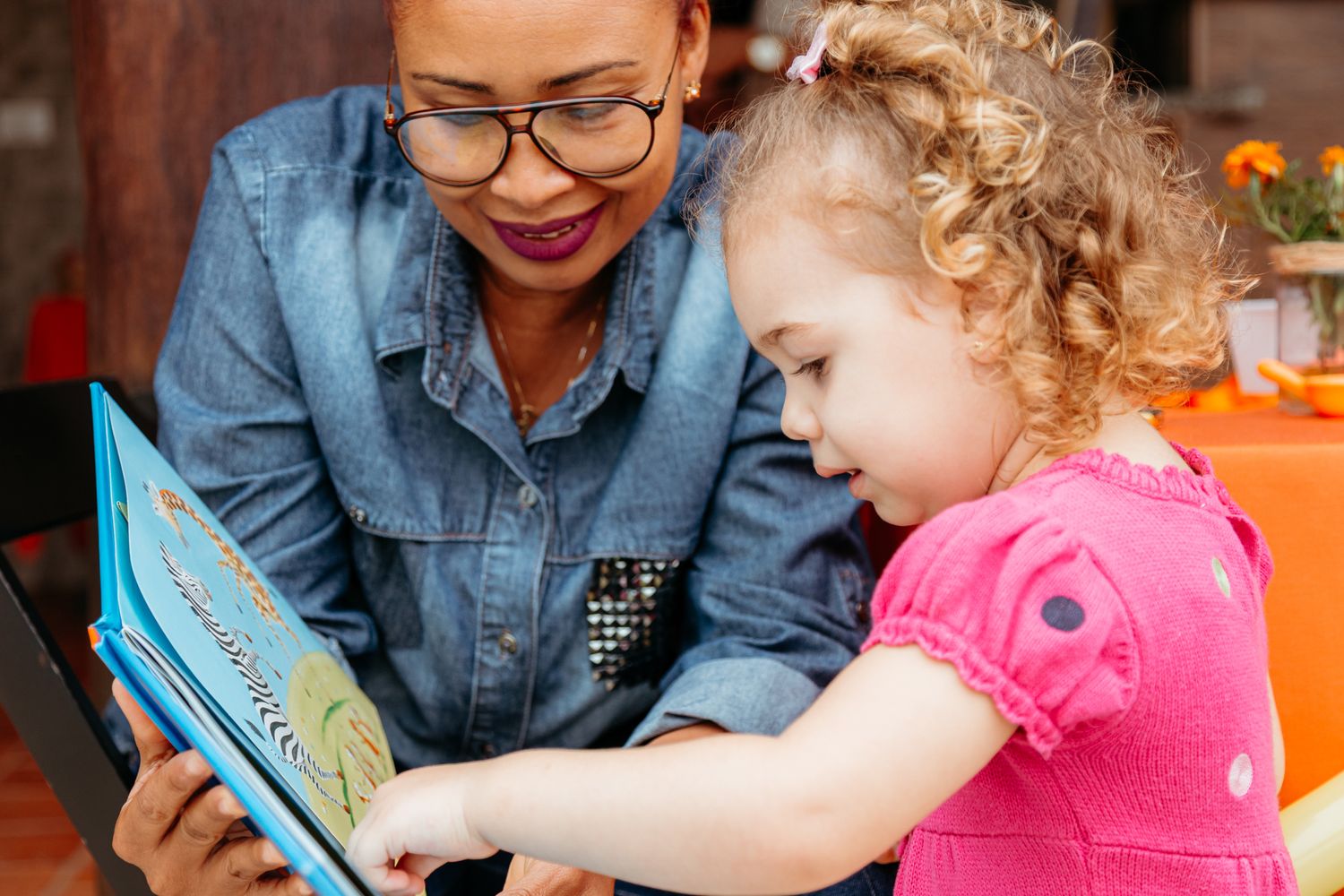Teacher and young student interacting with a tablet device during an educational activity in a classroom setting.